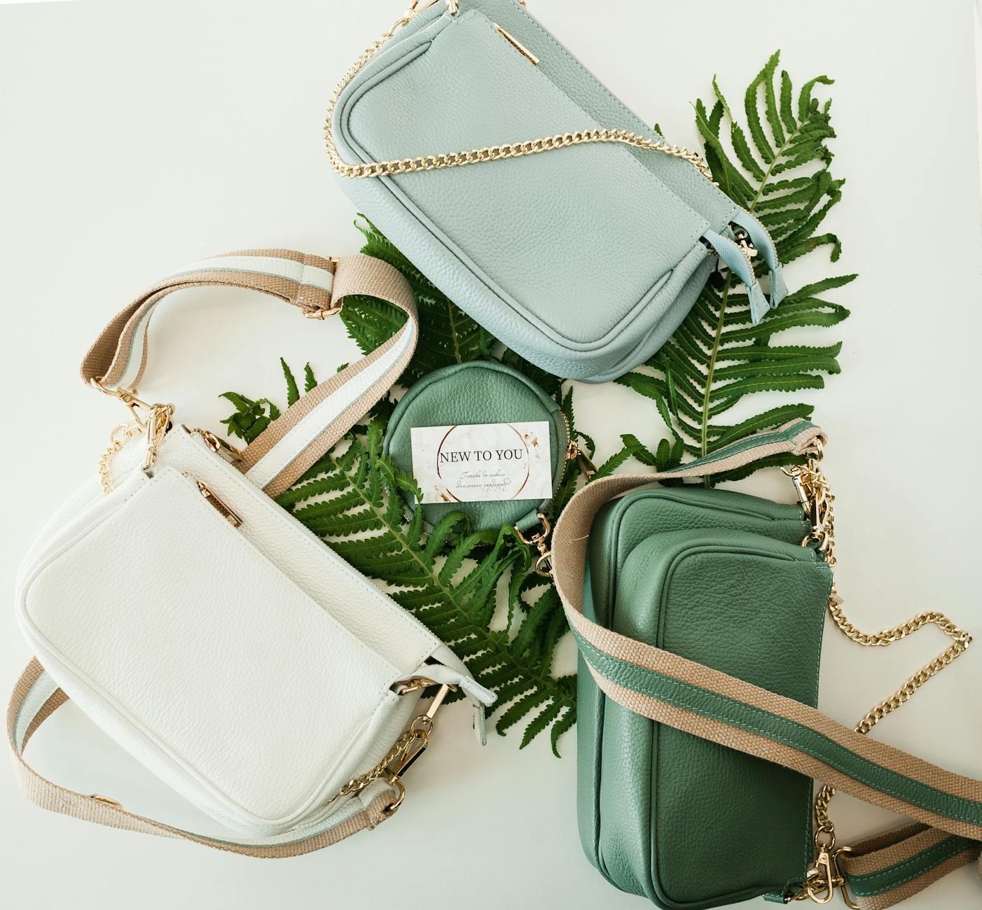 green gray and white leather handbags on fern leaves