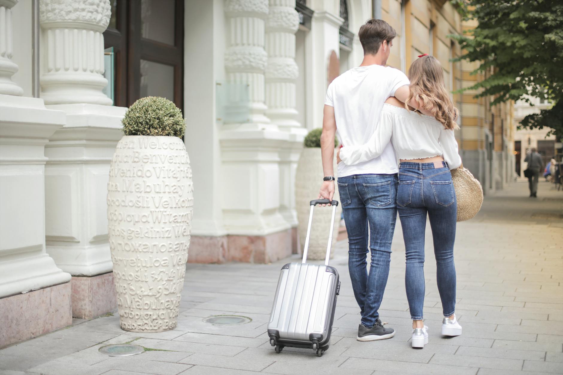 couple with suitcase walking along city street