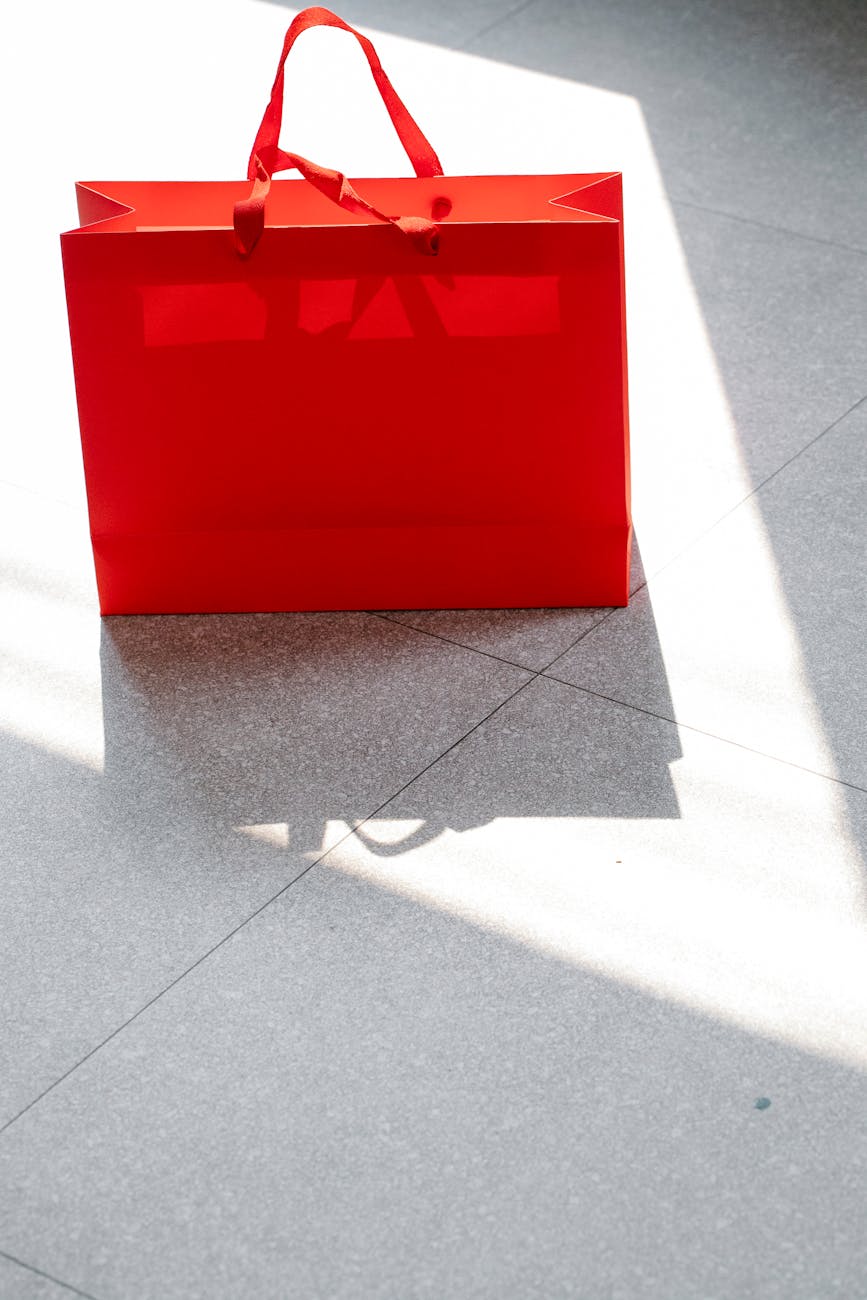 red shopping bag placed on tiled surface in sunlight