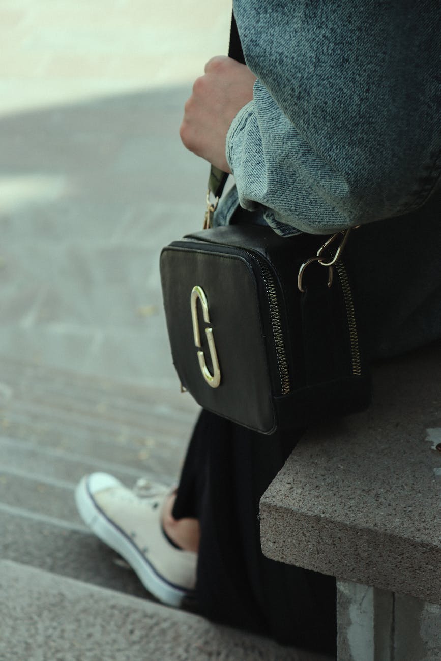 close up shot of a person sitting on a concrete bench while carrying marc jacobs bag
